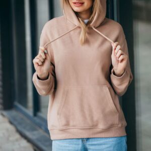 Lifestyle mockup of a cozy unisex sweatshirt on a model with warm neutral background and copy space for minimalist inspirational design (soft pink/blue accents).