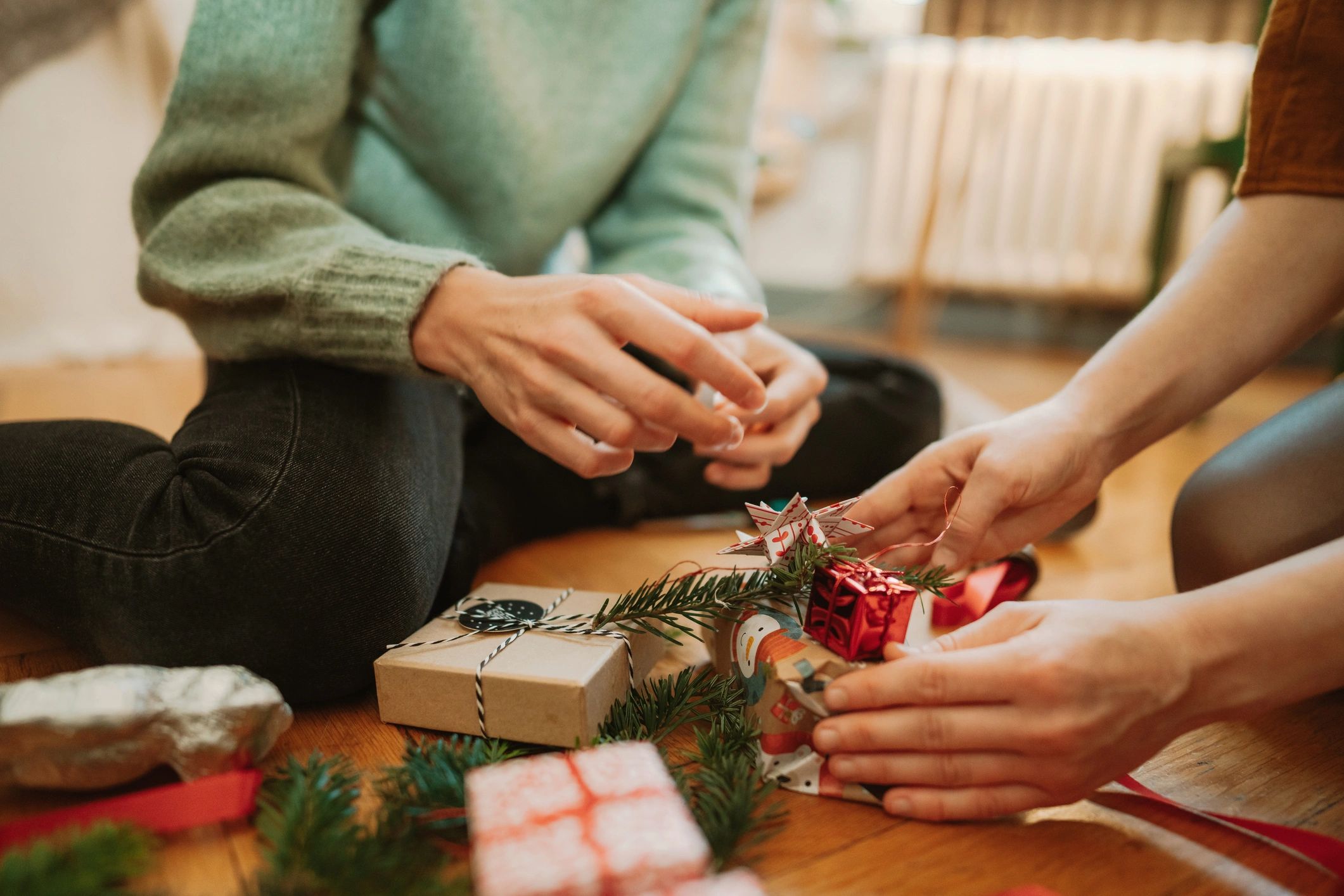Hands wrapping a gift with patterned paper and ribbon