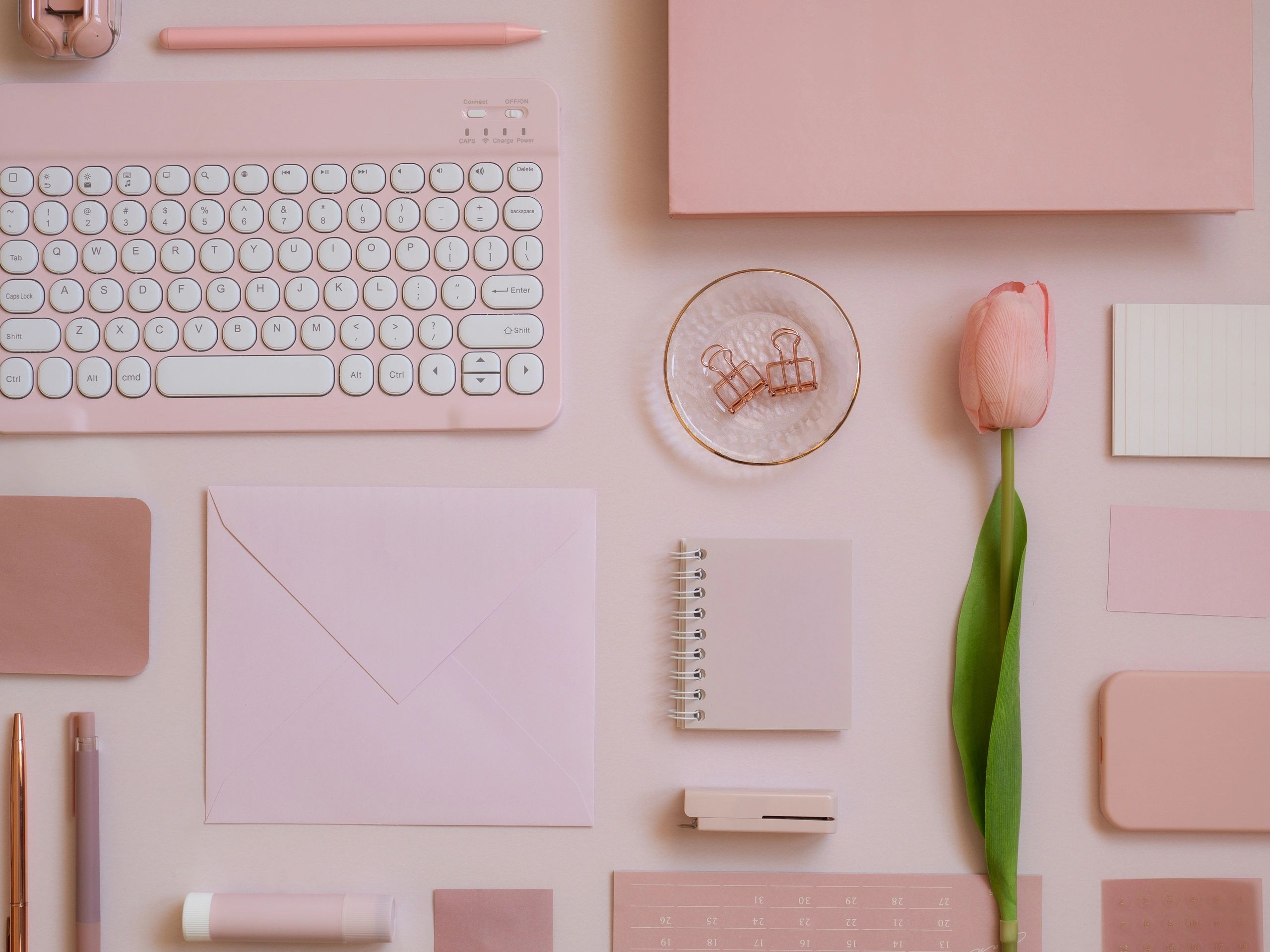 Pastel pink stationery flat lay on a desk