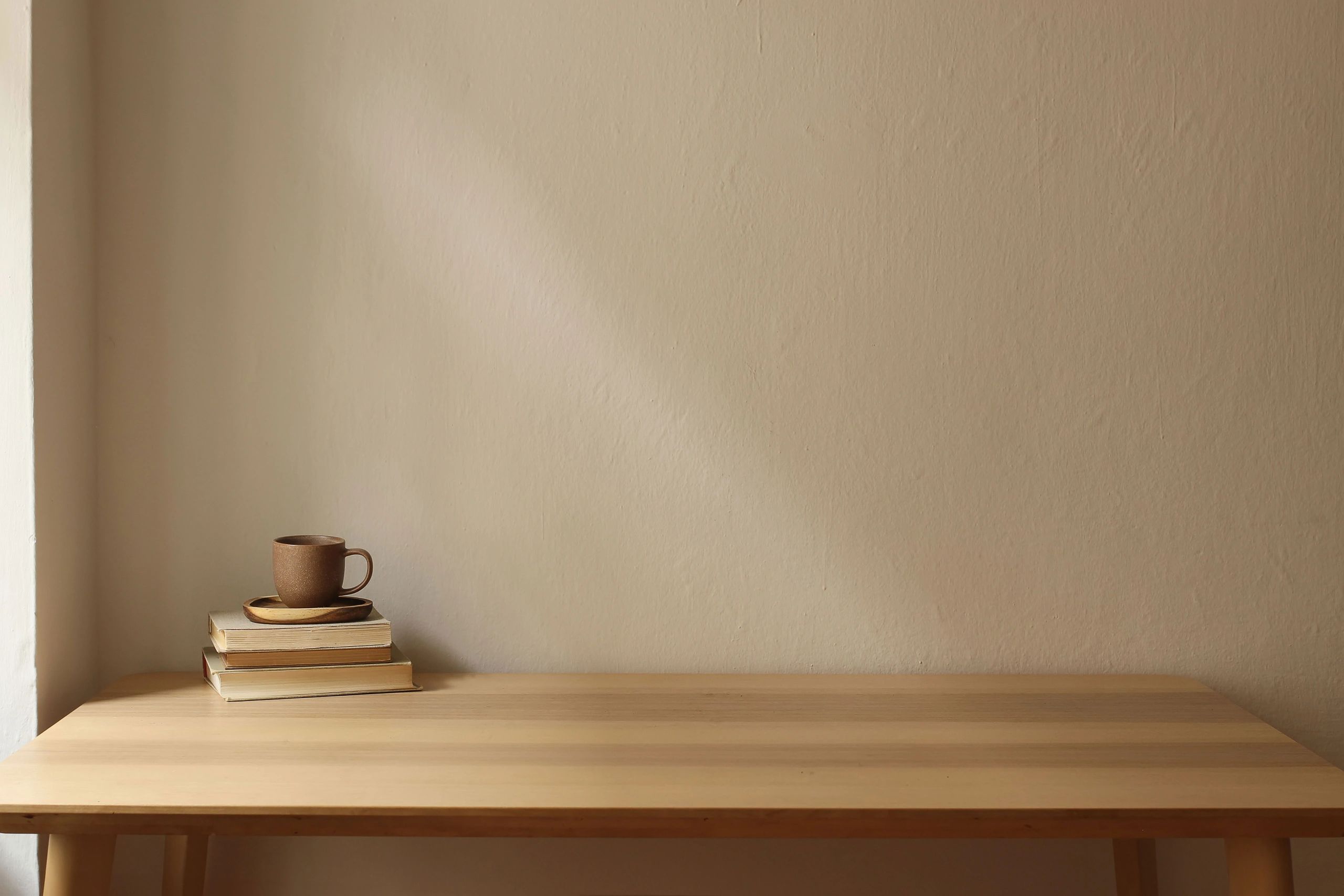 Styled product photo of a ceramic mug on a wooden table with warm cream background and copy space for a customizable name or message area (soft pink/blue accents).