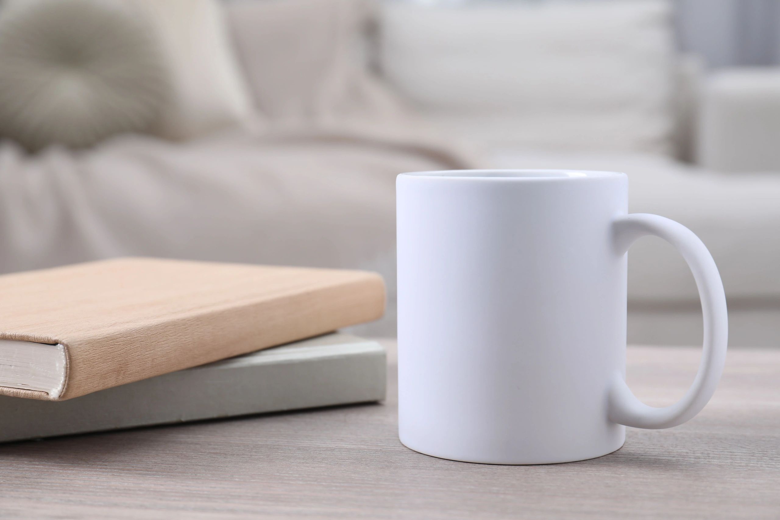 Blank ceramic mug mockup on a wooden table with notebooks